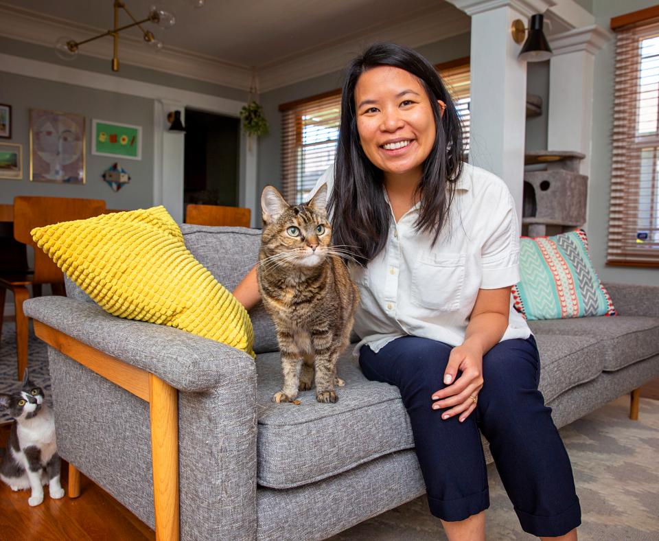 Smiling person sitting on a couch with a cat next to them