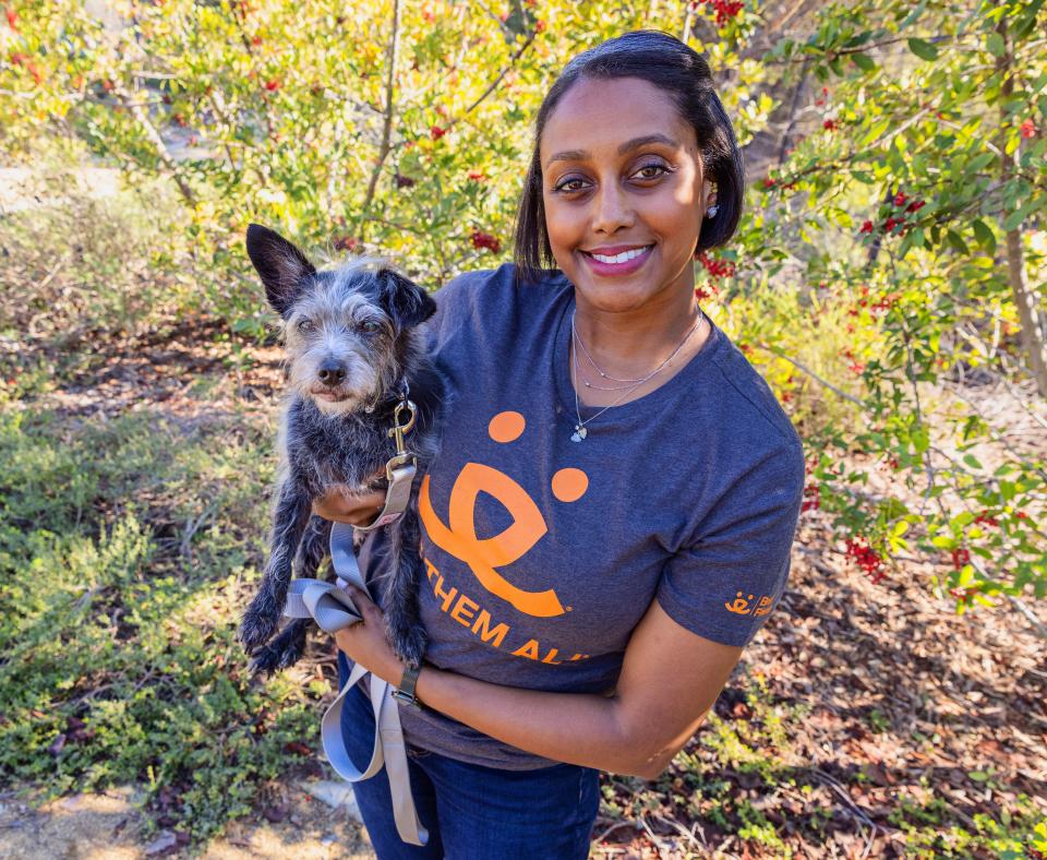 Smiling person holding a small dog outside