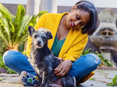 Smiling person sitting with a small dog outside