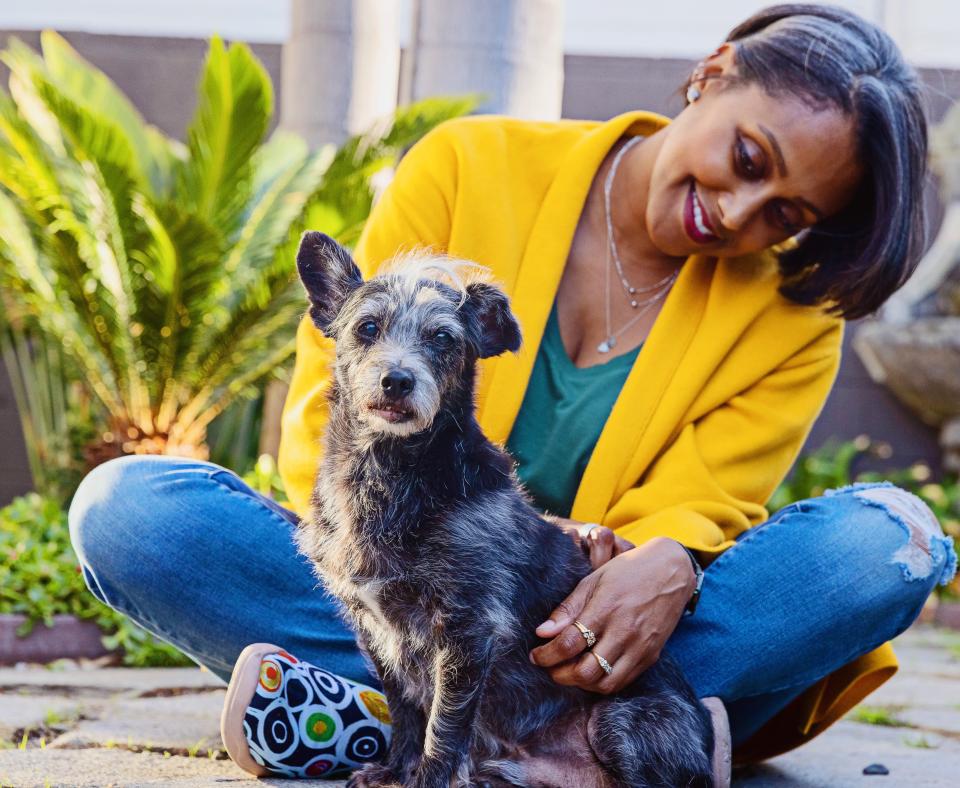 Smiling person sitting with a small dog outside