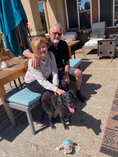 Francis the dog with a couple outside with one person petting him