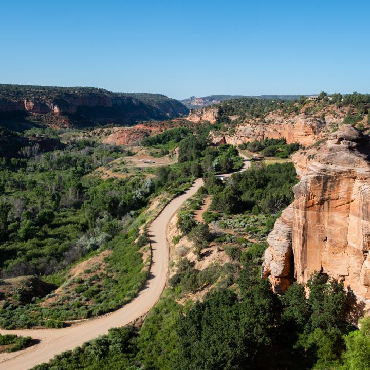 Road running through red rock canyon with blue sky