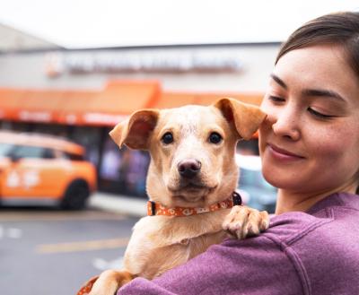 Person holding a small dog in front of a Best Friends location