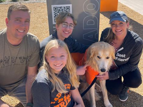 Caesar the dog with his new family outside in front of a Best Friends sign