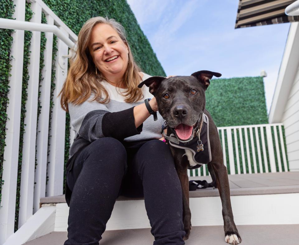 Smiling person sitting outside on steps with a happy dog