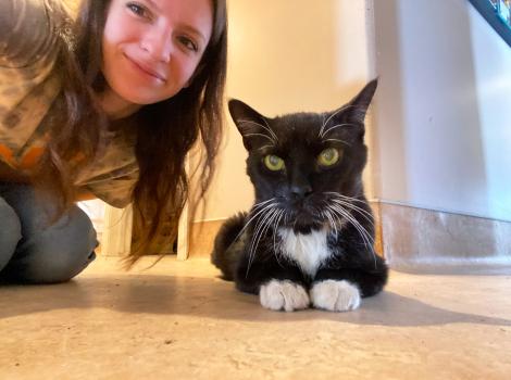 Petey the cat with Emily kneeling next to him