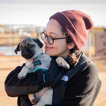 Darlene wearing a hat and holding a pug