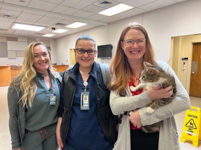 Three smiling people from UC Davis, one who is holding Dixon the cat