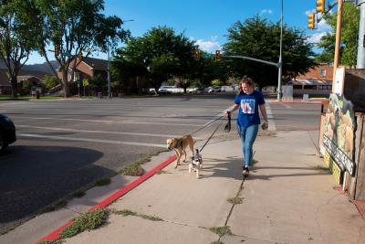 Anabel walking Dealla and Piper the dogs outside on a sidewalk