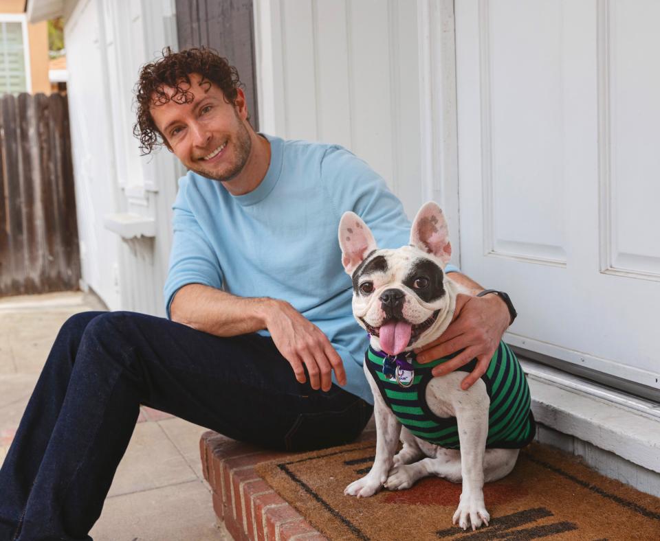 Smiling person sitting outside on some steps with a small dog