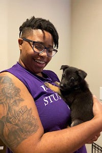 Tya smiling and holding a puppy