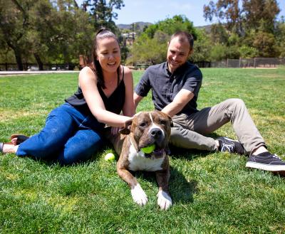 Smiling people sitting with a happy dog in the grass