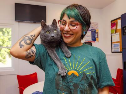 Person smiling while petting a cat on their shoulder