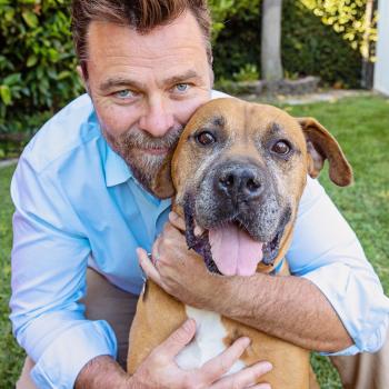 Man hugging large brown dog