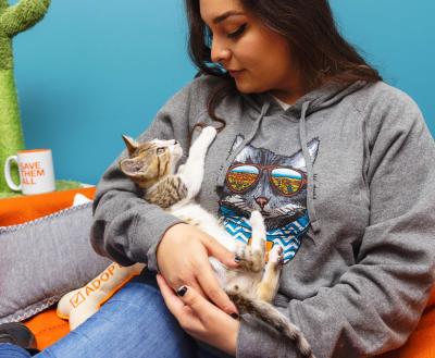 Person cradling a tabby and white kitten in her arms