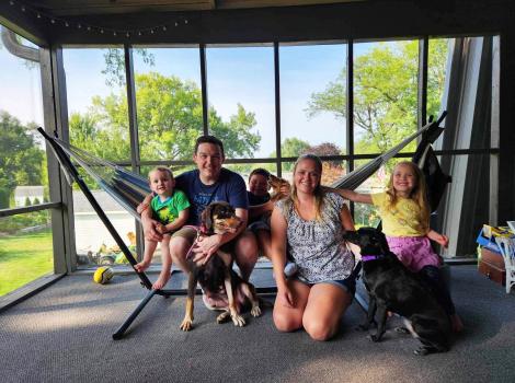 Family adopting Jewel the dog in front of a window