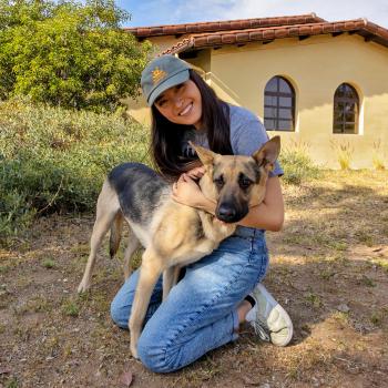 Smiling person kneeling down next to a dog