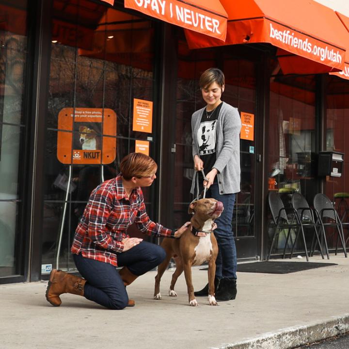 Man, woman and dog in front to Best Friends Adoption Center