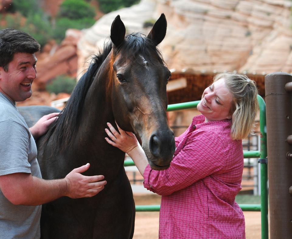 Two smiling people standing outside with a horse at Best Friends Animal Sanctuary