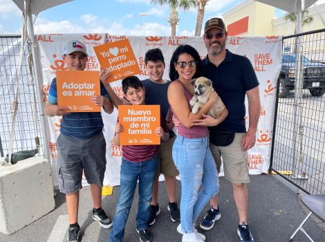 Family holding a puppy they adopted along with some Best Friends signs