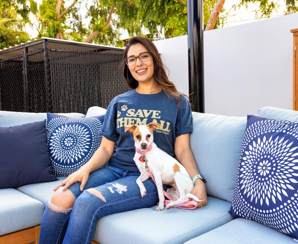 Smiling person wearing a Best Friends shirt on an outdoor couch with a dog