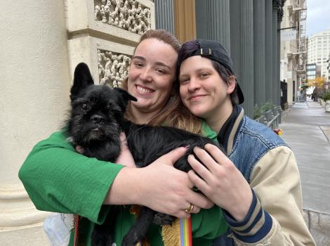 Two smiling people holding LaBamba the senior dog