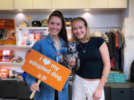 Sonny being held by Lilana and Lilyblue with a sign that says, "I heart my adopted dog"