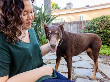 Woman outside, petting a Doberman-type dog