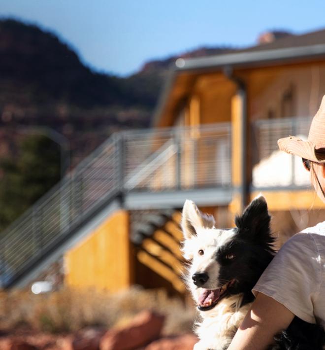 woman in hat carrying a dog