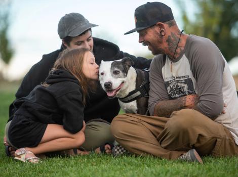 Rosita the dog with her new family, sitting outside on green grass