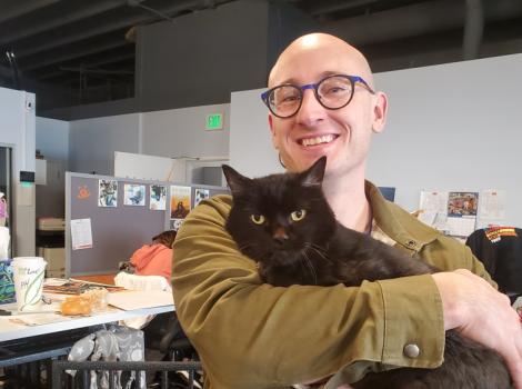 Smiling person holding Fossey the black cat