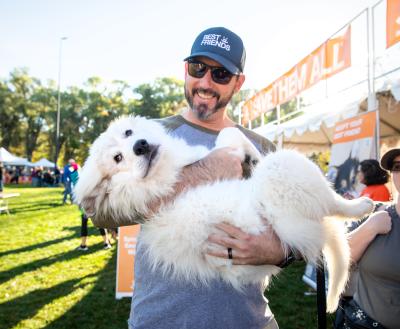 Smiling person holding a dog at Strut Your Mutt in Salt Lake City