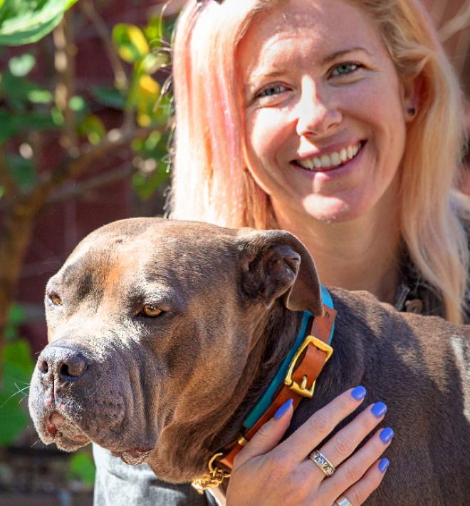 Person hugging a dog while sitting in a sunny garden