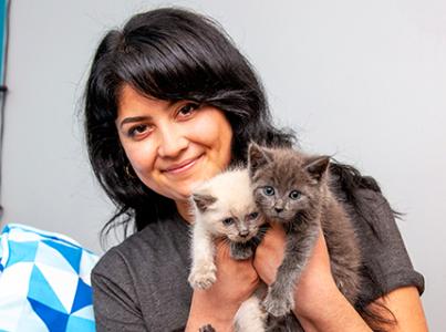 Smiling person holding pair of kittens