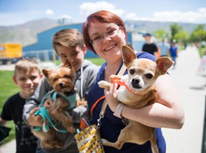 Smiling people holding two small dogs at a pet adoption event