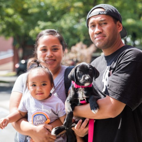 Family holding a black and white puppy